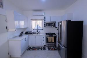 a kitchen with white cabinets and a black refrigerator at Sunset Sea-renity Villa in Belle Air Summit