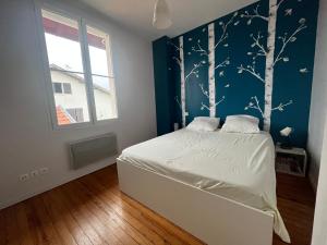 a bedroom with a bed with a blue wall at Villa des Loriots in Anglet +8 photos