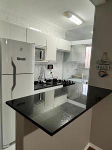 索罗卡巴Moderno e aconchegante ao lado do Iguatemi的厨房配有白色橱柜和黑色台面