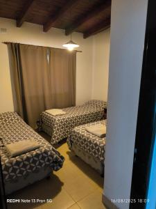 a room with three beds in a room with a beam at Cafayate Deptos in Cafayate