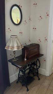 a room with a table with a lamp and a mirror at Petite maison de brocanteur à Charbonnières in Charbonnières-les-Bains
