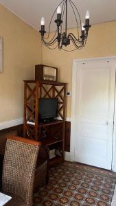 a room with a tv and a door with a chandelier at Petite maison de brocanteur à Charbonnières in Charbonnières-les-Bains