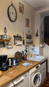 a kitchen with a counter with a clock on the wall at Petite maison de brocanteur à Charbonnières in Charbonnières-les-Bains