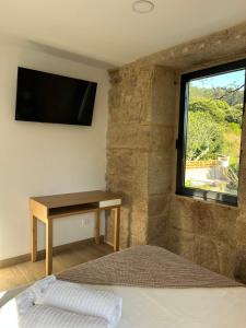 a bedroom with a desk and a window with a television at Casa rural Reibón in Moaña