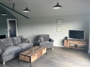 a living room with a couch and a tv at Stunning Contemporary Dutch Barn Conversion in Whixall