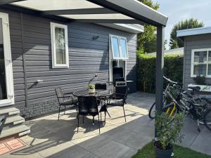 a patio with a table and chairs and a house at Huis Frieda am See, Nähe Arnheim in Lathum +26 photos