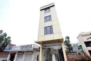 a tall white building with a balcony on a street at Hotel O Sky in Zirakpur