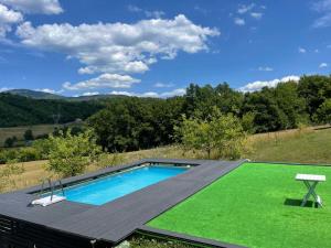 a swimming pool with a green lawn next to it at Vikendica Krupa in Banja Luka