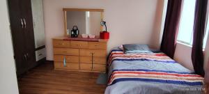 ein Schlafzimmer mit einem Bett, einer Kommode und einem Spiegel in der Unterkunft Departamento El Mirador Concax in Los Baños del Inca