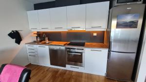 a kitchen with white cabinets and a stainless steel refrigerator at Korshamn in Lyngdal +21 photos