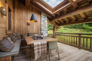 une terrasse en bois avec une table et un banc dans l'établissement Prestigious 7BR Alpine Chalet - Sauna, Home Cinema & Mont Blanc Panorama, à Megève