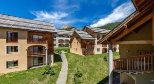 a group of buildings with mountains in the background at Appartement 4 pièces pour 6-8 personnes, 3 chambres, 2 canapés-lit double dans le salon, au pied des pistes et piscine l'été, wifi fibre in Arvieux