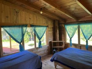 two beds in a room with two windows at Cabaña El Descanso del Carpintero in La Marquesa