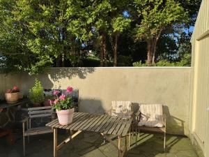 a picnic table and two chairs with flowers on a patio at Leilighet i villa, 3 soverom med parkering-nær sentrum - Open for ONS 2026 in Stavanger