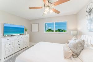 a bedroom with a white bed and a ceiling fan at Across from Beach | Balcony • Pool • Parking • 2BR in Boca Raton +43 photos