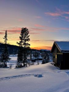 ein Haus im Schnee mit dem Sonnenuntergang im Hintergrund in der Unterkunft Brand new cabin on the sunny side of Gaustatoppen with a beautiful view in Tuddal