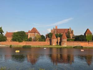 a castle sitting next to a large body of water at Apartament Przedzamcze Malbork in Malbork