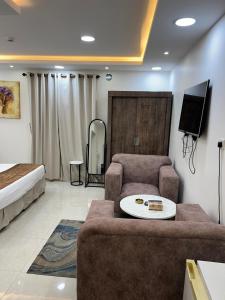 a living room with a couch and a tv and a bed at Adeem Serviced Apartments in Buqayq
