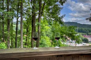 two glasses of red wine sitting on a wooden railing at New Alpenrosen Haus-Arcade Hot Tub Sauna Views in Helen