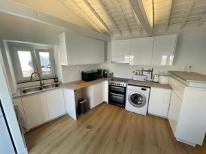 a kitchen with white cabinets and a washing machine at Casa do Nitsa in Corvo