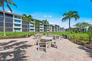 a patio with tables and chairs in front of a building at Steps To The Beach Loggerhead 472 in Sanibel