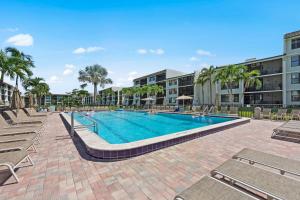 a swimming pool with lounge chairs and a building at Steps To The Beach Loggerhead 472 in Sanibel