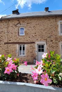 a brick house with pink flowers in front of it at La Maison des Rosiers in Manhac