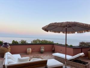 a patio with an umbrella and chairs and a couch at Casa Della Baia With a beautiful view in Varazze