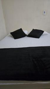 a bed with black and white sheets and pillows at Rancho Petite Fleur in Aparecida do Taboado +32 photos