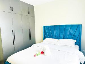 a bedroom with a blue headboard and a white bed at Urban Stays-Two bedroom Near JKIA Airport in Nairobi