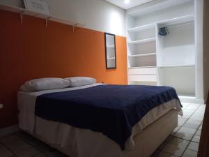 a bedroom with a large bed with an orange wall at Historico Edf Oceania in Boa Viagem in Recife