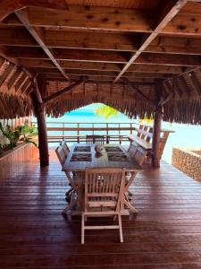 a wooden deck with a table and chairs and the ocean at GAIA BEACH AND LAGOON - At Tiahura place in Haapiti +16 photos