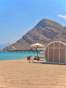 a beach with a table and an umbrella and the water at Ground peaceful chalet 3 bedroom with 6 king bed & 2 bathrooms &private garden marvelous land escape Murano resort Ain sokhna in Ain Sokhna