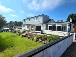 a white house with a fence in a yard at Four Winds Holiday Let in Nairn