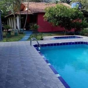 a swimming pool in front of a house at Sítio Isolina Piscina, Campo e Lago in Juquitiba