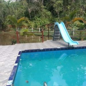 a slide in a swimming pool next to a swimming pool at Sítio Isolina Piscina, Campo e Lago in Juquitiba +4 photos