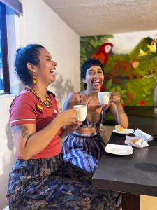 two women sitting at a table drinking coffee at Hostal Galería de la Montaña, Medellin in Estación El Salto