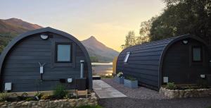 two black tiny homes with mountains in the background at Loch Leven Pods in Kinlochleven