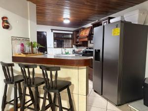 a kitchen with a bar with stools and a refrigerator at Tico Airport B&B in Alajuela