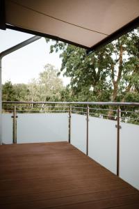 a wooden deck with awning and trees in the background at Panorama-Seeblick, Privater Steg, Balkon, Parkplatz in Plön