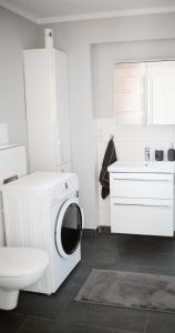 a white bathroom with a washing machine and a sink at Panorama-Seeblick, Privater Steg, Balkon, Parkplatz in Plön +28 photos