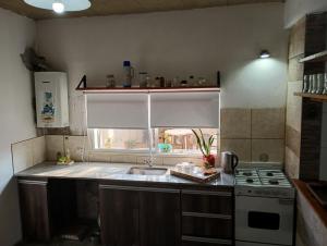 a kitchen with a sink and a stove and a window at HTA Hospedaje Turismo Aventura in San Fernando del Valle de Catamarca