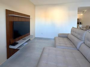 a living room with a couch and a flat screen tv at Oasis das Dunas in Cabo Frio