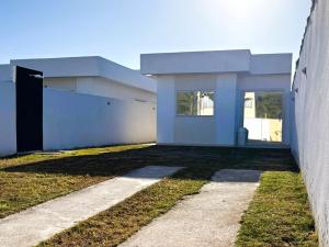 a white building with a door next to a yard at Oasis das Dunas in Cabo Frio