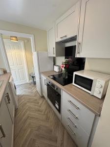 a kitchen with white cabinets and a microwave at Birks Terrace - 2 Bedroom - Sleeps 4 in Cleator Moor