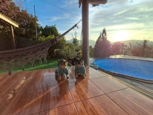two stuffed animals sitting on a porch next to a swimming pool at Chalé cipreste 4 Quartos in Gramado