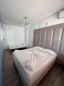 a bedroom with a large white bed with a large headboard at Vila Behar - Penthouse Apartment in Sarandë