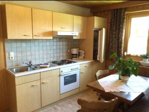 a kitchen with a sink and a stove and a table at Winklgut Bacher in Uttendorf