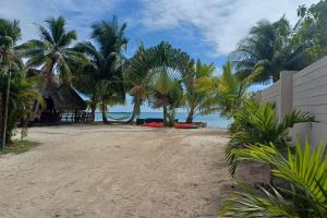 a sandy beach with palm trees and the ocean at GAIA BEACH AND LAGOON - At Tiahura place in Haapiti