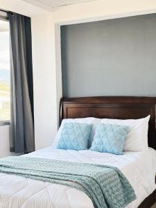 a bed with a blue and white blanket on it at Apartamento céntrico y acogedor en Tegucigalpa in Tegucigalpa
